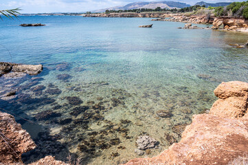 Fototapeta na wymiar Beautiful beach with crystal clear water and a natural rock arch in the background in Syracuse Sicily