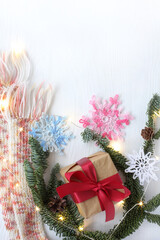 gift, knitted snowflakes and a scarf with fir branches in the lights of garlands top view. warm mood of the winter holiday
