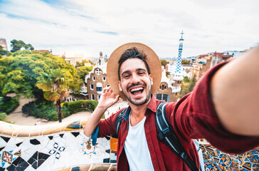 Happy tourist take selfie self-portrait with smartphone in Park Guell, Barcelona, Spain - Smiling man on vacation looking at camera - Holidays and travel concept - obrazy, fototapety, plakaty