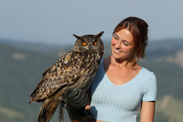 Happy falconer looking at eagle owl outdoor