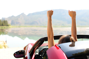 Driver celebrating rsising arms in a convertible car