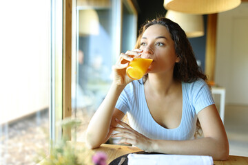 Woman drinking orange juice from glass in a restaurant