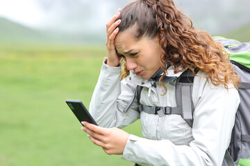 Worried hiker checking phone in the mountain