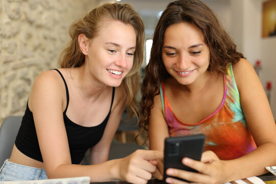 Friends checking phone together in a restaurant