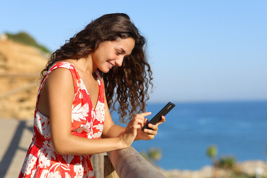 Woman on summer vacation on the beach using phone
