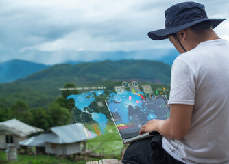 In a faraway location, a young Asian man utilizes the Internet and a computer to communicate with customers.