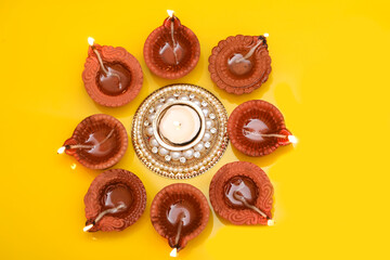 Concept of indian festival diwali. Traditional oil lamps on yellow background.