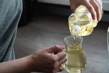 Sunflower oil is poured out of a plastic bottle on the kitchen table.