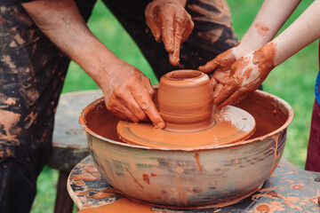 Father and son making ceramic pot. Family working on pottery wheel. Potters and child hands.