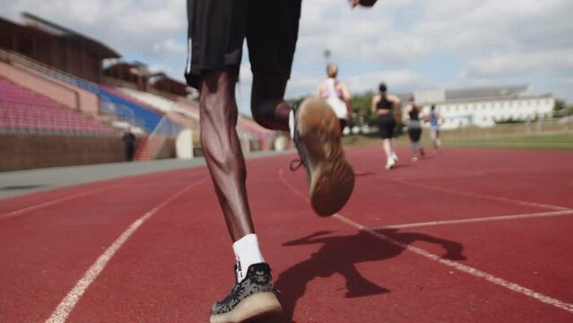 Black male athlete running low start, slide shooting. Legs of a black runner at the stadium training for the race, close-up