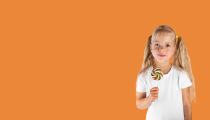 Beautiful girl with candy on a stick on apricot crush background. Horizontal orientation, copy space.