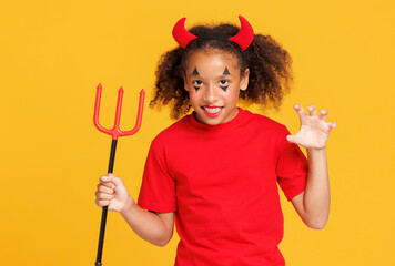 Happy cheerful ethnic girl in devil costume scary   gestures and celebrates Halloween  on a bright...