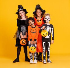 Happy Halloween! Kids in carnival costumes and makeup with pumkin basket smiling on bright colored...