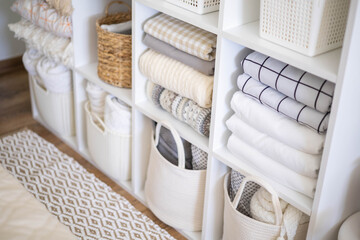Neatly folded linen cupboard shelves storage at eco friendly straw basket placed closet organizer