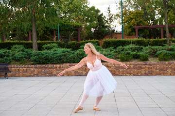 Fototapeta na wymiar Mature woman dancing ballet in a park at street.