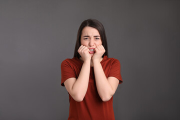 Portrait of emotional young woman on dark grey background. Personality concept