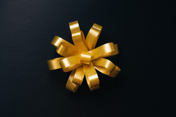 Golden bow for present on black background. Top view. Black friday or Christmas holidays concept