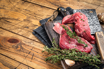 Raw Sirloin flap or Bavette raw beef meat steak on a wooden butcher board with meat cleaver. Wooden...