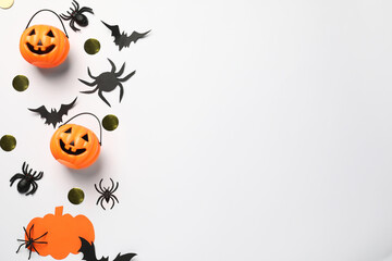 Flat lay composition with plastic pumpkin baskets, paper bats and spiders on white background, space for text. Halloween celebration