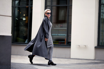 Elegant Mature woman walks city street , wears stylish clothes, gray wool coat, long dress, black...