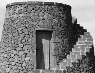 Old tower with wooden door and stairway built of tufa stone