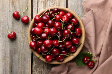 Fresh ripe cherries and towel on wooden table, flat lay
