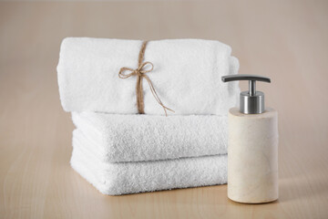 Obraz na płótnie Canvas Soft towels and dispenser on wooden table