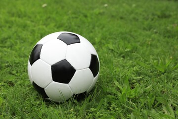 Soccer ball on green grass outdoors, space for text