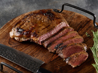 Grilled beef heart steak with pepper on a wooden board.