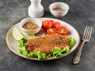Breaded pork cutlet with cherry tomatoes, mustard and lemon.