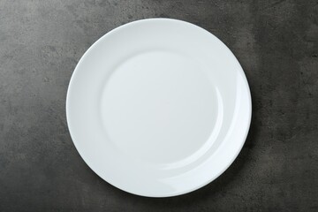 Empty white ceramic plate on grey table, top view