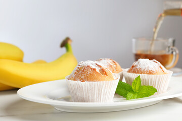 Tasty muffins served with mint on white table, closeup