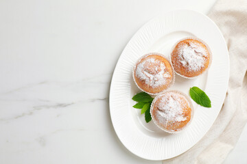 Tasty homemade muffins served with mint on white marble table, top view. Space for text