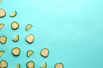 Slices of fresh ripe cucumber on turquoise background, flat lay. Space for text