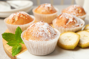 Tasty muffins served with mint and banana on board, closeup