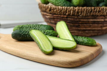 Whole and cut fresh ripe cucumbers on white table