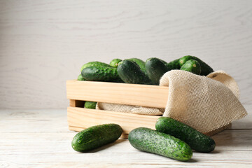 Crate full of fresh ripe cucumbers on white wooden table
