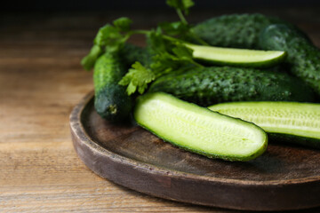 Fresh ripe cucumbers and parsley on wooden table, closeup