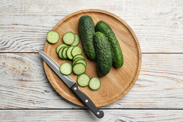 Whole and cut fresh ripe cucumbers on white wooden table, flat lay