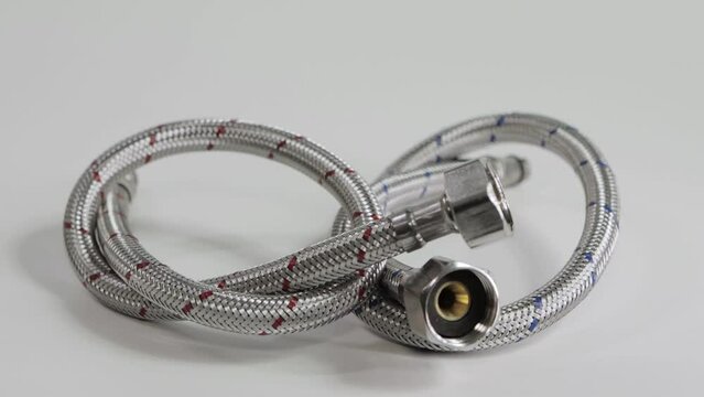 Hoses in a metal braid for cold and hot water on a white background. Plumbing, close-up