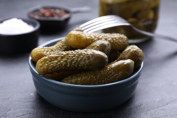 Bowl of pickled cucumbers and ingredients on black table, closeup