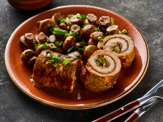 Pork roulade with pickles and bacon, served with fried mushrooms and green onions