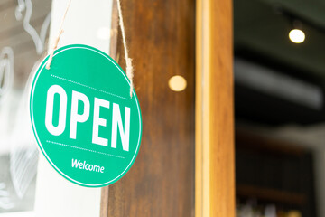 Open sign hanging on the entrance door. Close up of OPEN WELCOME notice sign board label hanging...