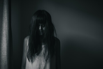 Female ghost in white dress in room. A young scary girl in an old white dress staring in to the...