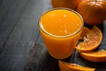 glass of fresh orange juice with fresh fruits on dark wooden table, high Vitamin C, orange drink