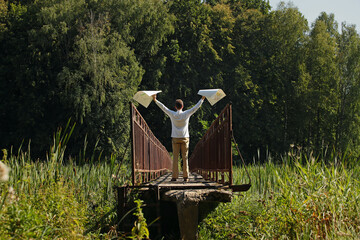 Young man artist with raised hands and drawings in hands on a narrow bridge. Pavel Kubarkov, i on narrow bridge with my drawings in hands. Photo was taken 24 August 2022 year, MSK time in Russia. - 535187206