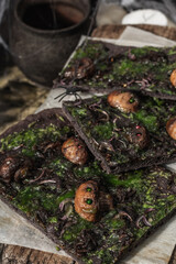 Halloween concept food. Flatbread or pizza with squid Ink, green cheese, mushrooms and purple onion