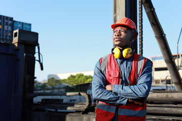Foreman engineer standing and crossed arms while looking away with happy and success face. Confident engineering work at container cargo site and checking industrial container cargo freight ship
