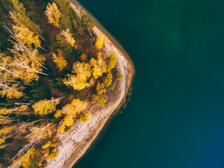 Aerial view of fall forest with autumn color trees and blue lake