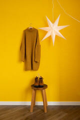 A knitted sweater hangs on a hanger on a yellow wall